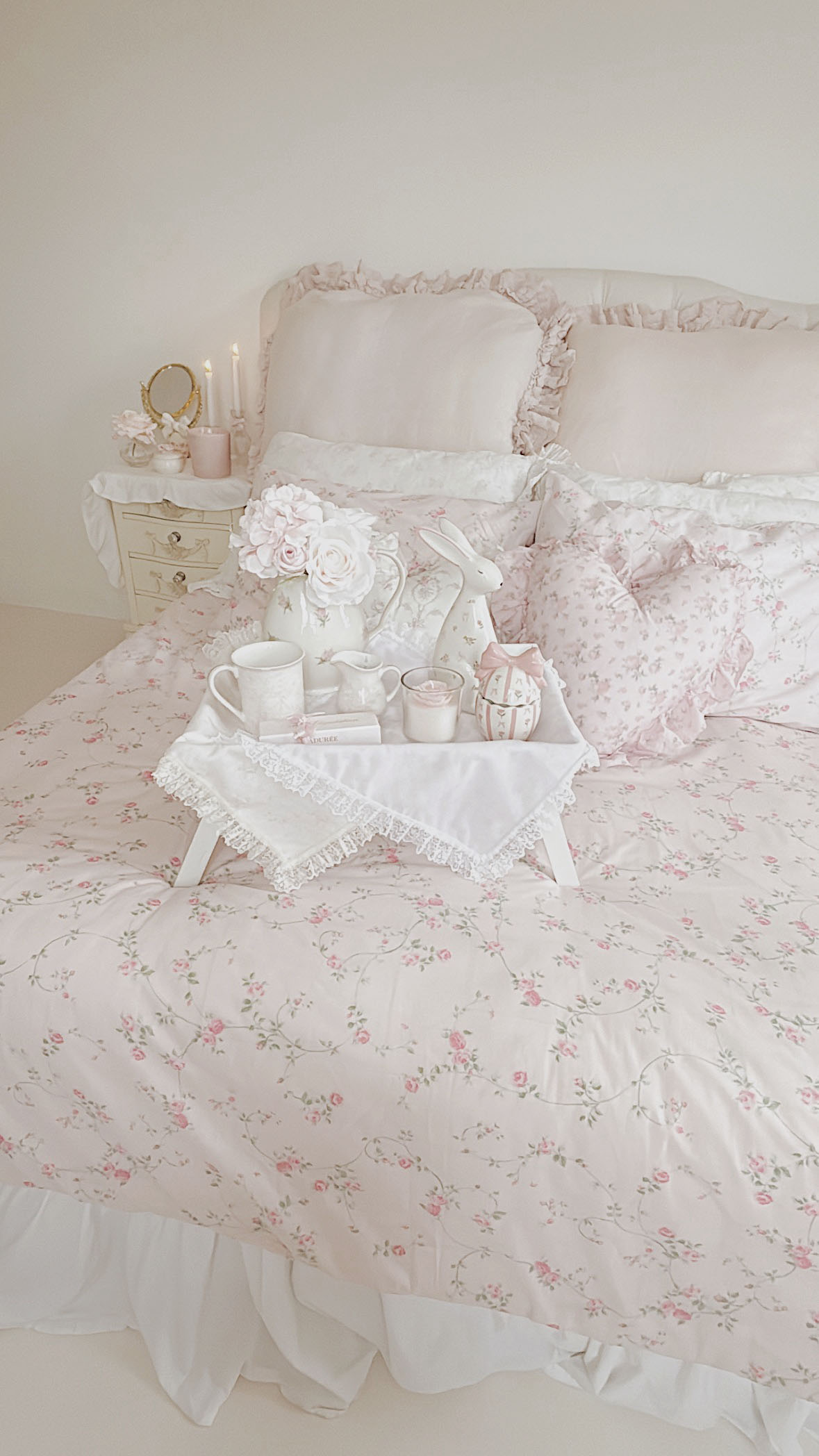 Aesthetic tea time styling with a rose printed teacup a milk jar and fresh spring flowers in a pink handpainted rose vase
