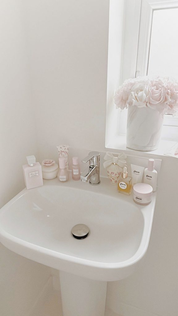 Shabby Chic bathroom sink with pink beauty products from Dior and Glow Recipe.