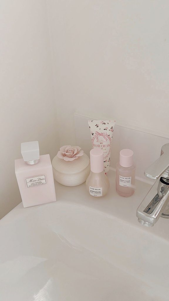 Shabby chic bathroom sink with pink Dior beauty products Glow Recipe and floral hand cream
