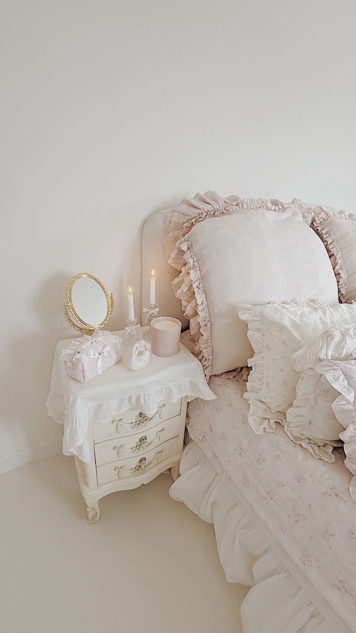 Romantic Shabby Chic bedroom featuring Rachel Ashwell pink floral bedding and a vintage nightstand with lace details.